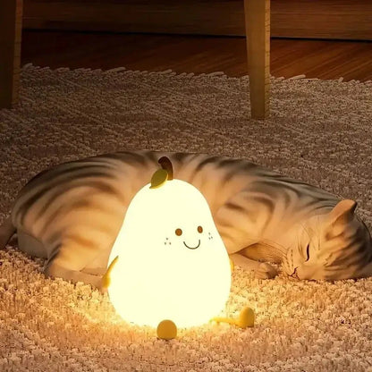 Chat tigré allongé sur un tapis derrière une veilleuse en forme de poire éclairée en jaune